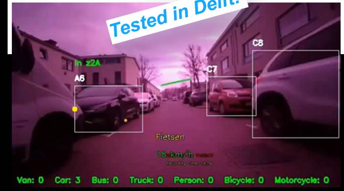 Camera view with detection boxes around parked and passing cars